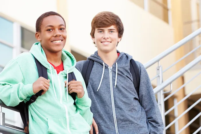 two boys with backpacks outside school
