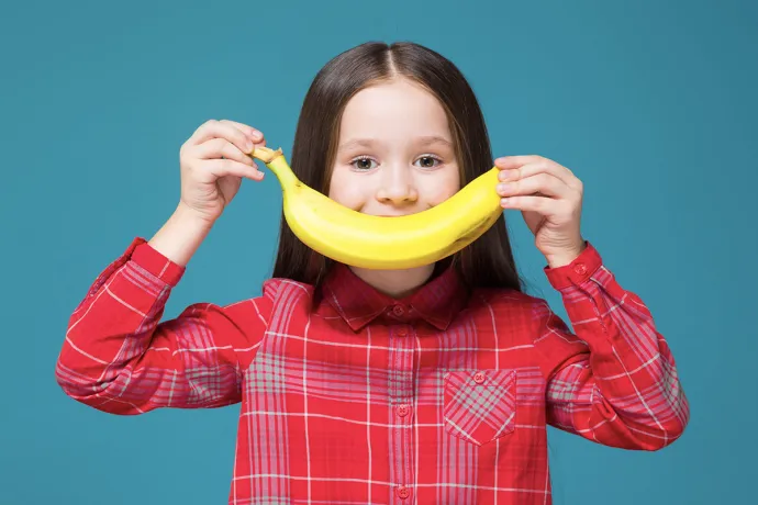 girl holding a banana that looks like a smile